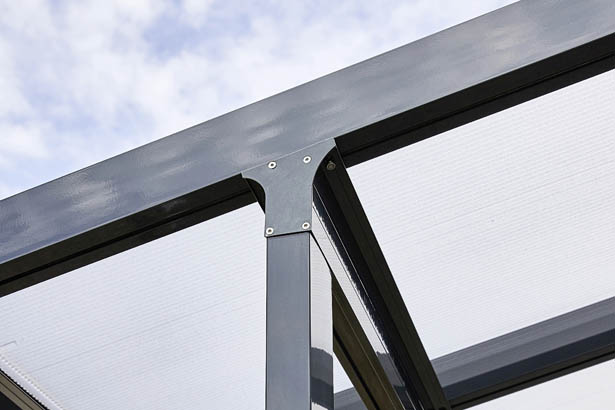 Eine Metallstruktur stützt ein transparentes Dach, mit leicht bewölktem Himmel im Hintergrund.