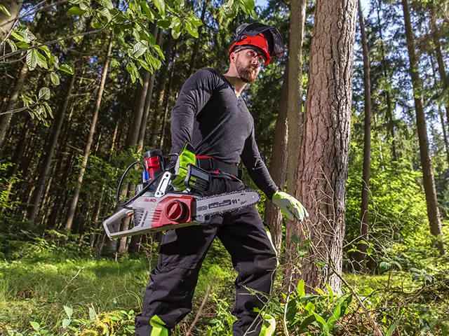 Mann mit Schutzkleidung und Mototsäge im Wald