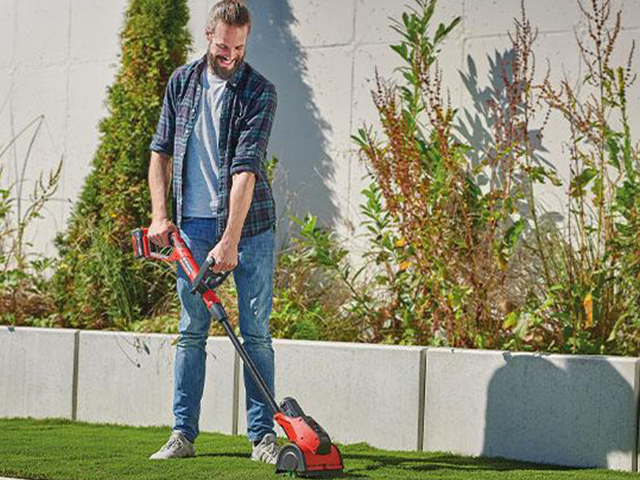Mann reinigt Fugen im Garten