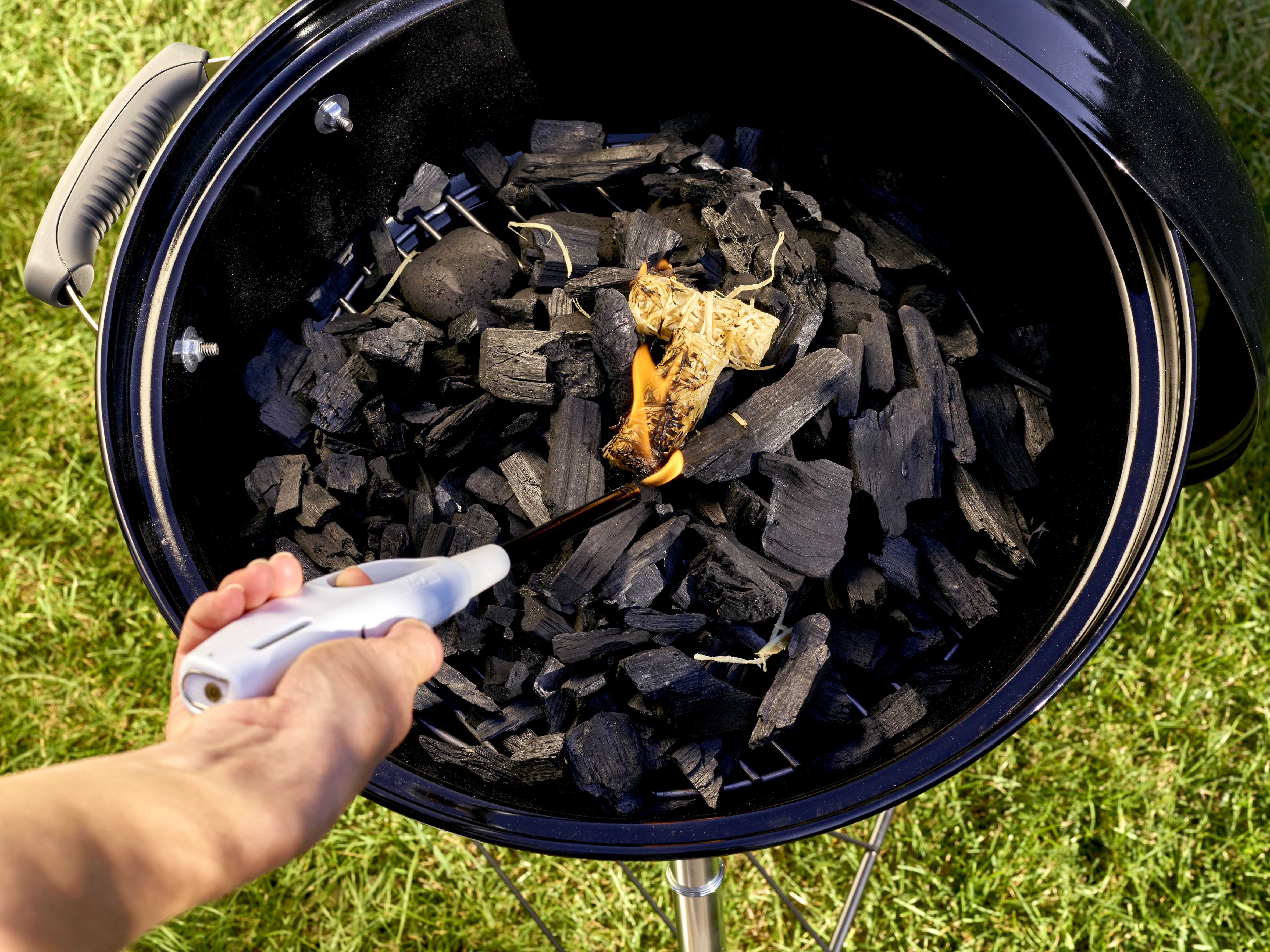 Holzkohle die gerade durch ein Feuerzeug angemacht wird