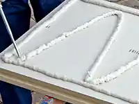 Ein Handwerker trägt Schaum auf eine Holzplatte im Freien auf.