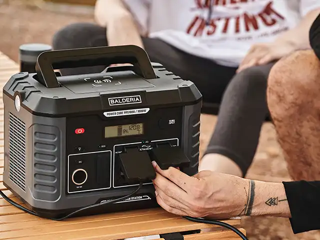 Eine tragbare Powerstation wird von einer Person im Freien auf einem Tisch bedient.