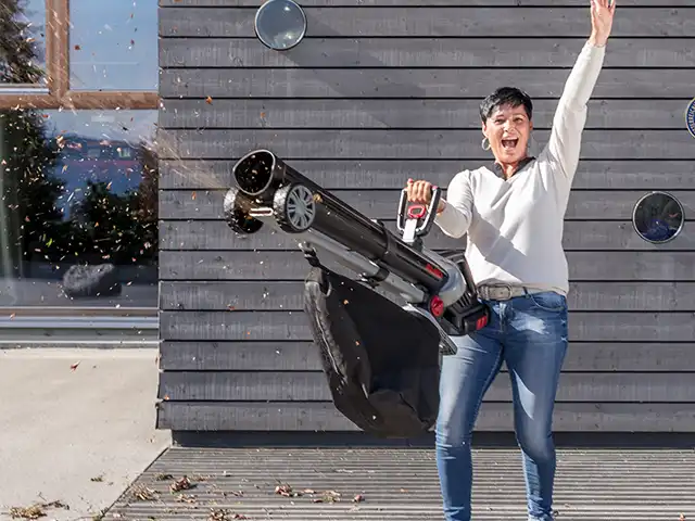 Frau jubelt mit Laubsauger in der Hand