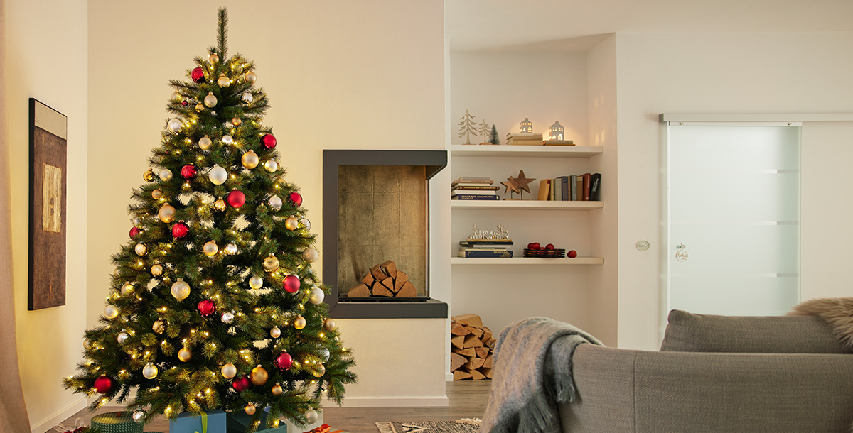 Künstlicher, geschmückter Weihnachtsbaum in einem Wohnzimmer Künstlicher, geschmückter Weihnachtsbaum in einem Wohnzimmer